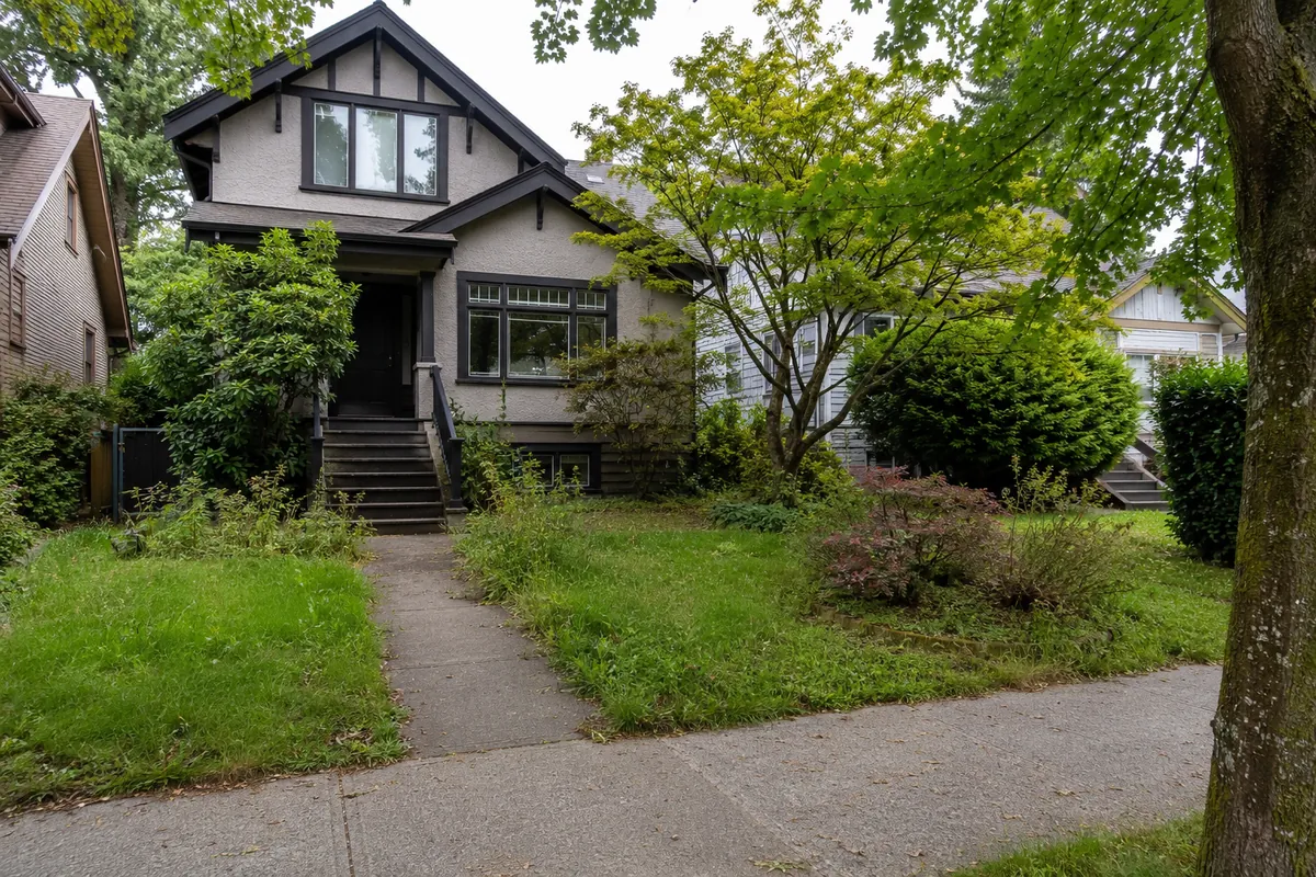 Residential front yard before landscaping work, with overgrown lawn and garden beds