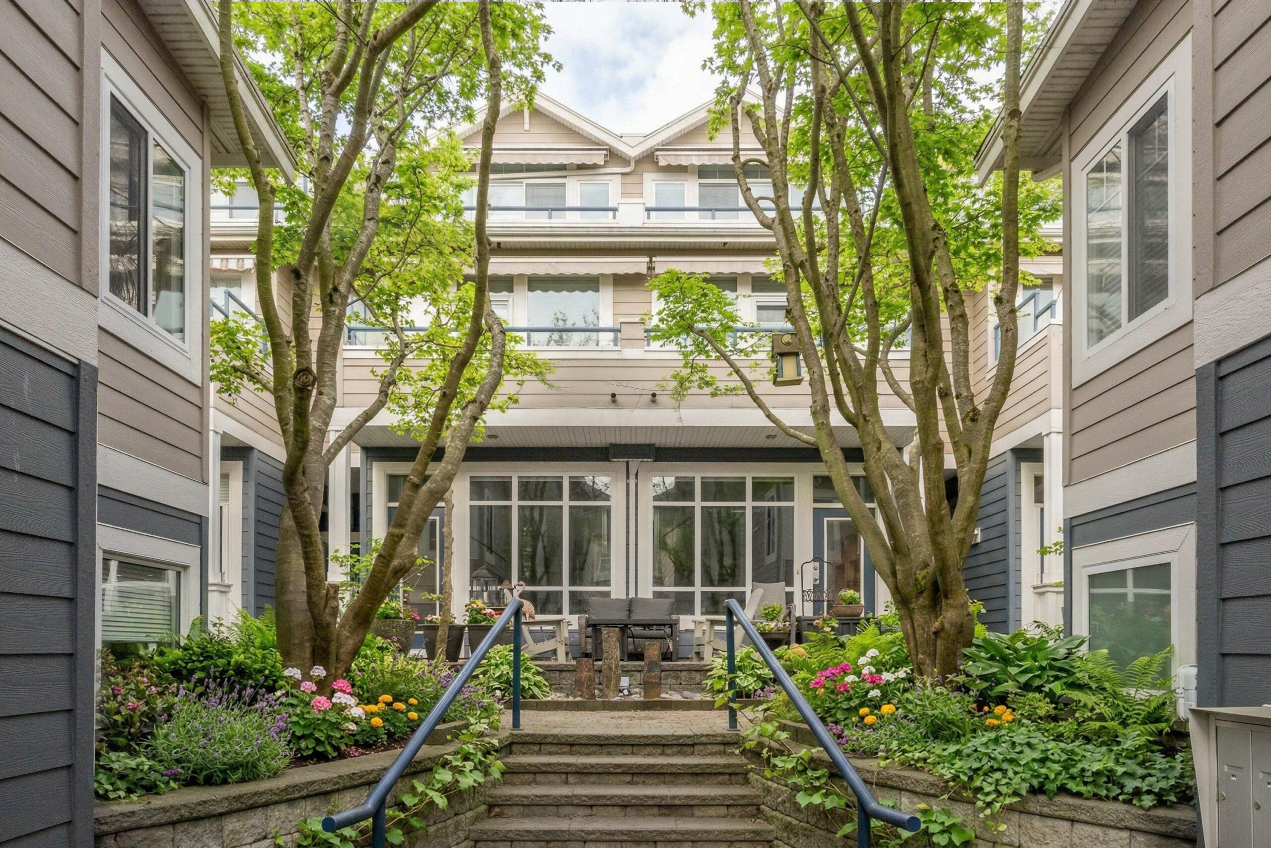 Residential courtyard with mature trees, flowers, and landscaped steps