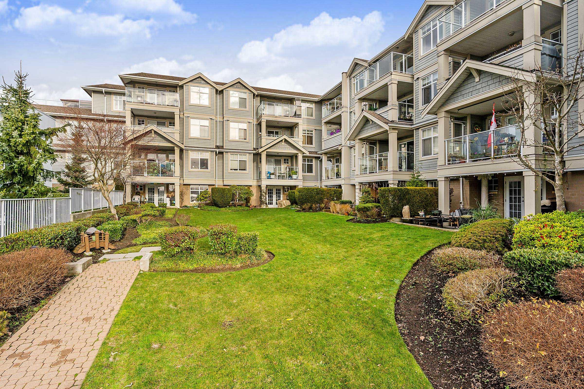 Condominium courtyard with lawn, pathways, and hedges